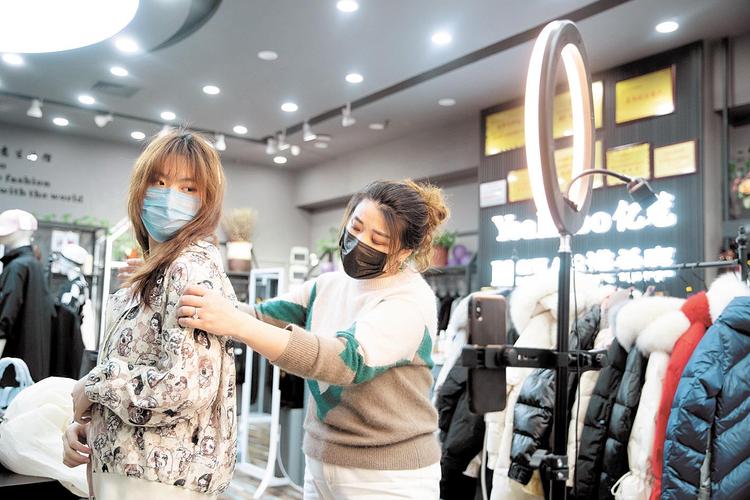 3月29日,武汉汉口北品牌服装城,卖家和主播一同通过直播卖服装.